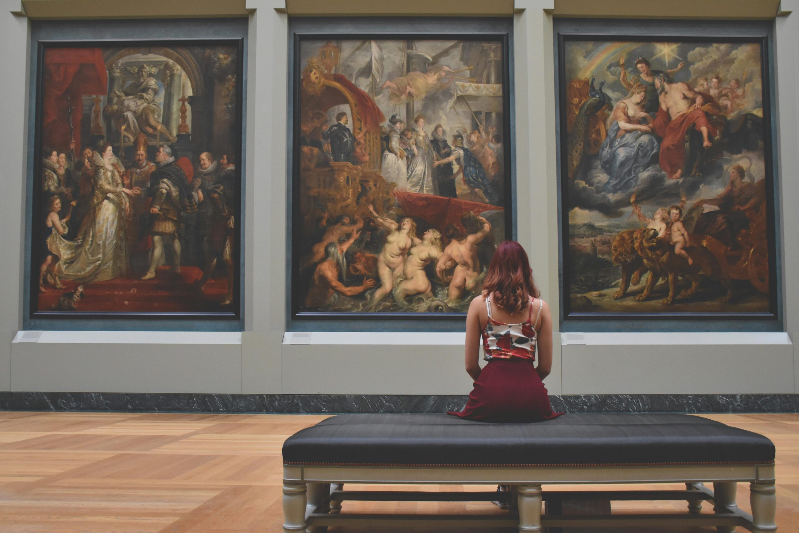 Woman sitting in a museum looking at art to describe how art makes you feel 